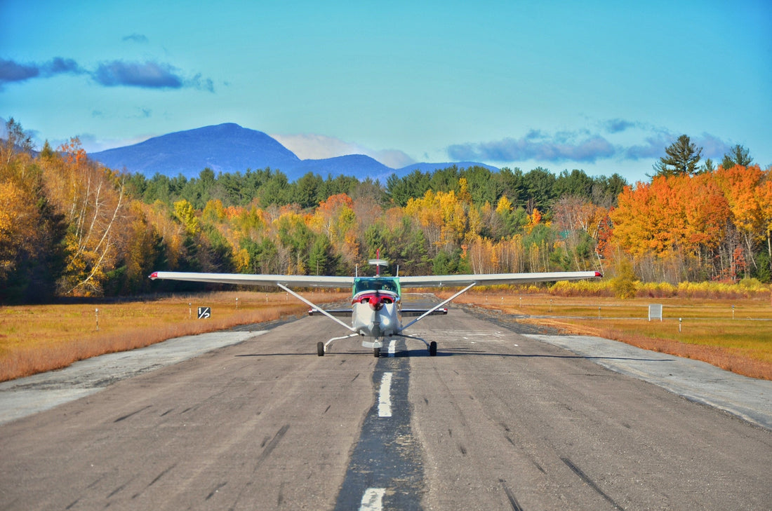 Small training aircraft on a rural New England runway with autumn foliage in the background, symbolizing student pilot training and regional aviation.