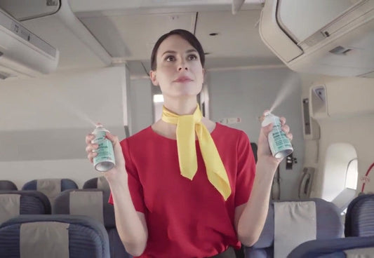 Flight attendant performing aircraft disinsection by spraying insecticide aerosols in an airplane cabin, following international health protocols.