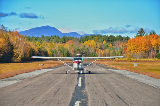 Small training aircraft on a rural New England runway with autumn foliage in the background, symbolizing student pilot training and regional aviation.