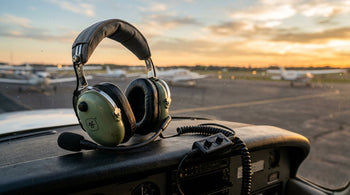 David Clark H10-13X ENC aviation headset resting on an aircraft glareshield at sunset