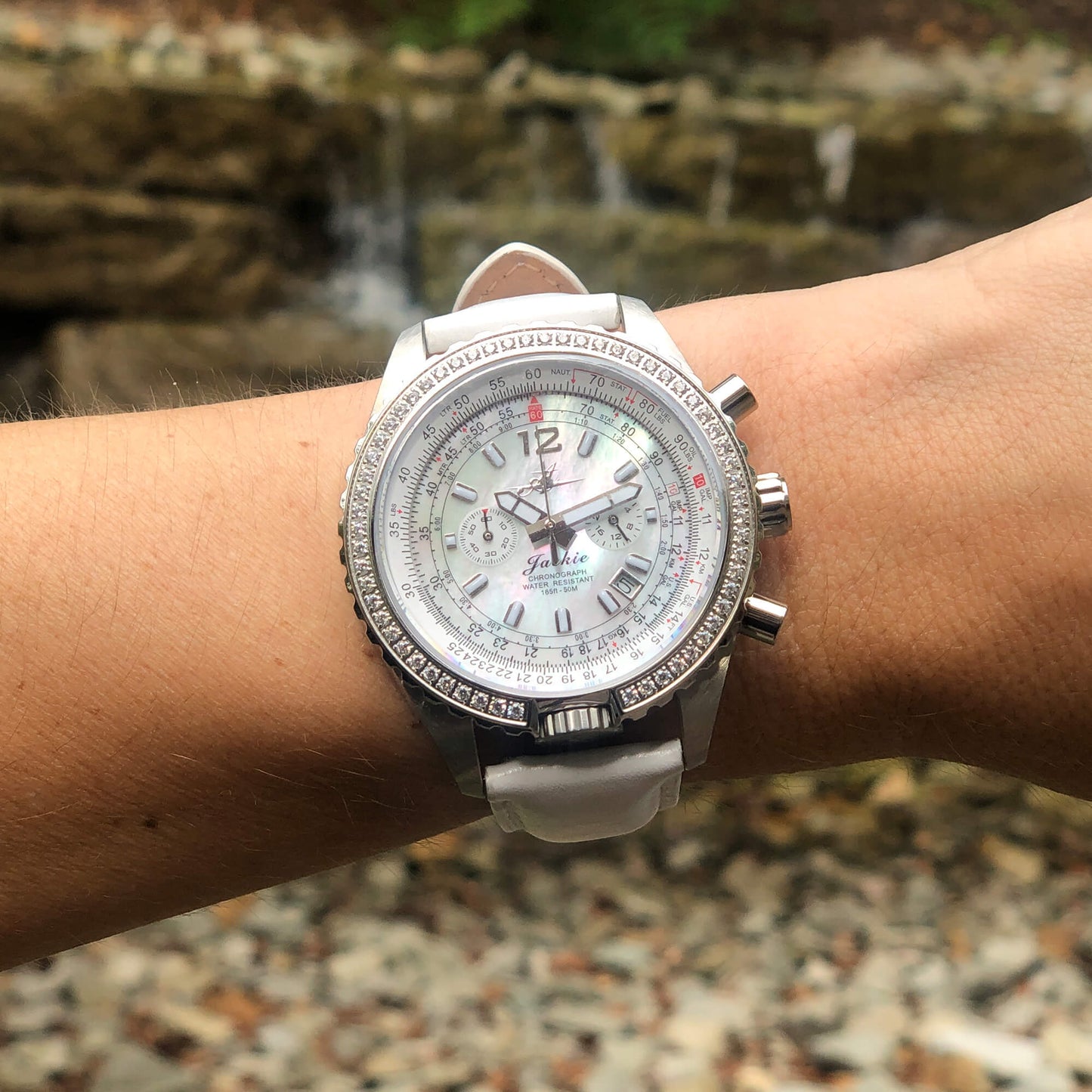 Jackie Women’s Pilot Watch with Dreamy White Mother-of-Pearl Dial, Swarovski Crystal Bezel, and White Leather Band on Wrist Outdoors