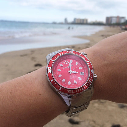 Marina Women's Dive Watch with Reef Red Dial and Titanium Bracelet, Shown on Wrist at the Beach with Ocean Background