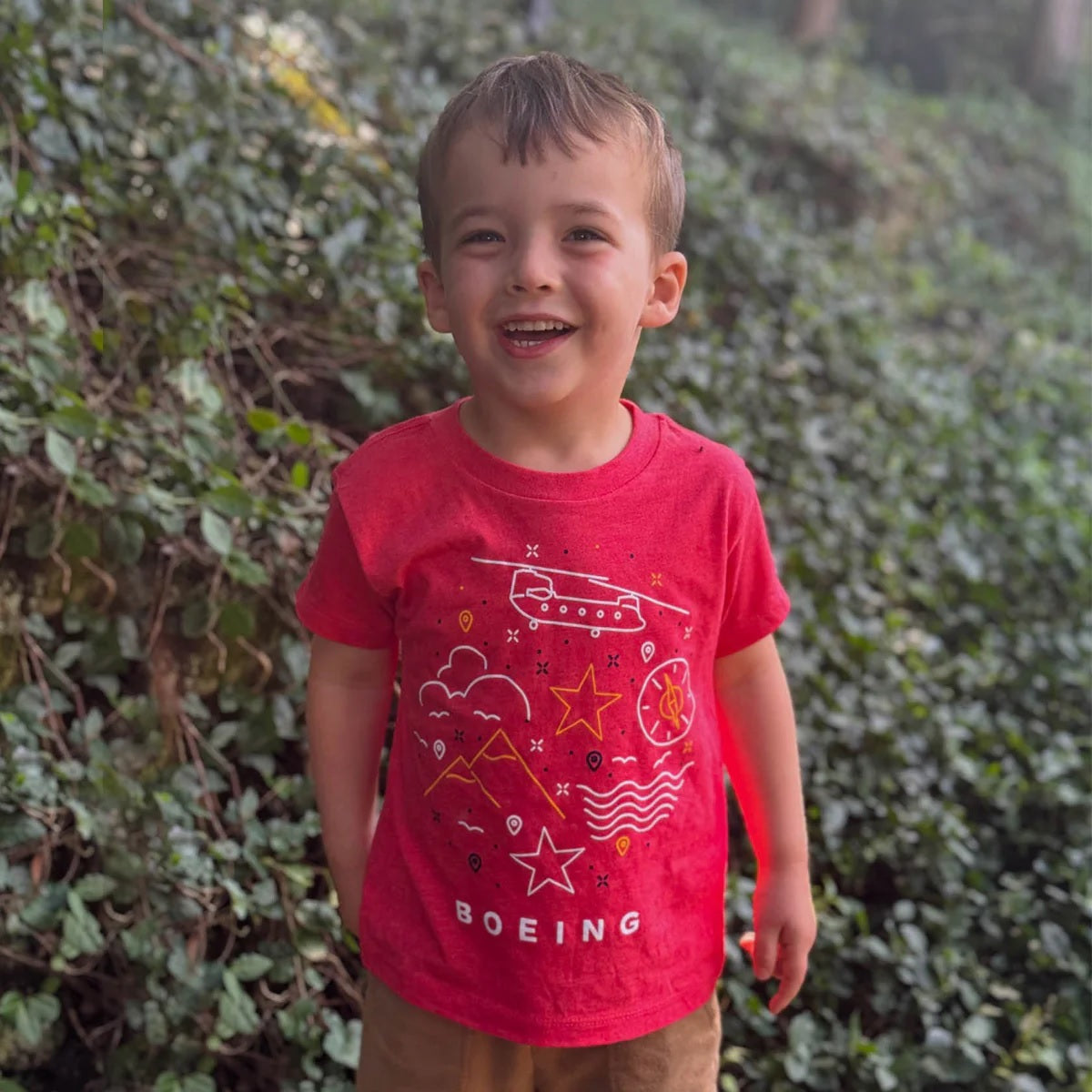 Toddler wearing red Boeing Defense Doodle t-shirt with aircraft and aviation doodle design