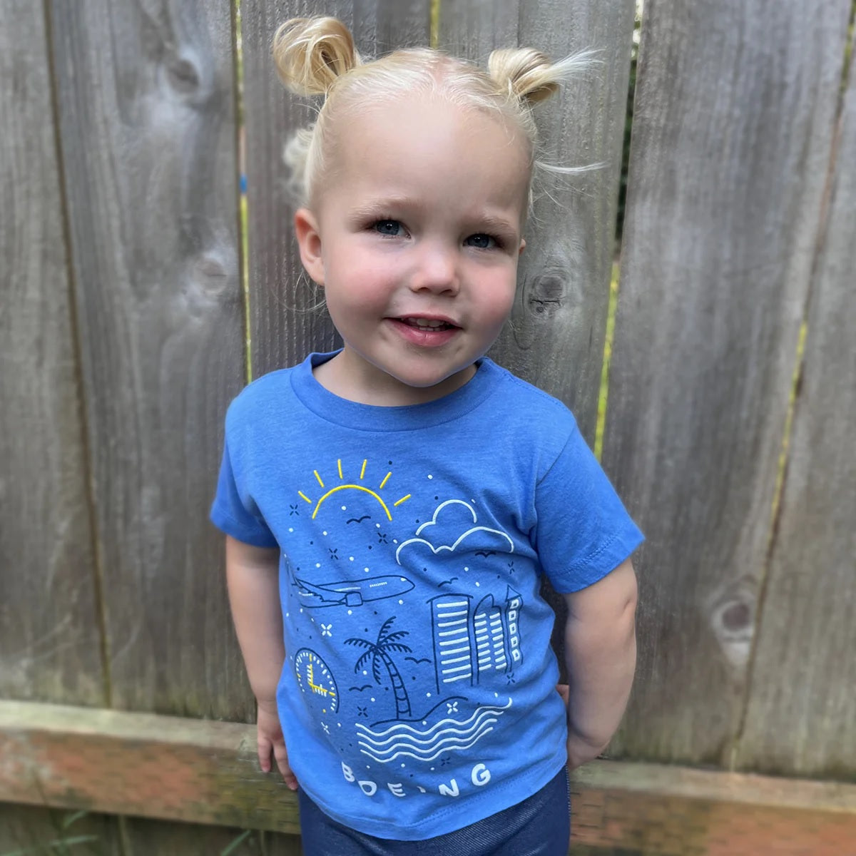 Toddler wearing Boeing Commercial Doodle t-shirt with illustrated airplane design outdoors
