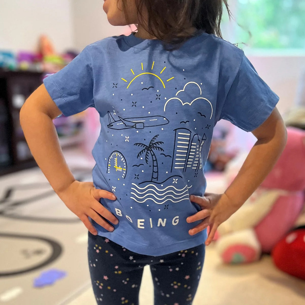 Child wearing Boeing Commercial Doodle toddler t-shirt showing airplane and city doodle artwork
