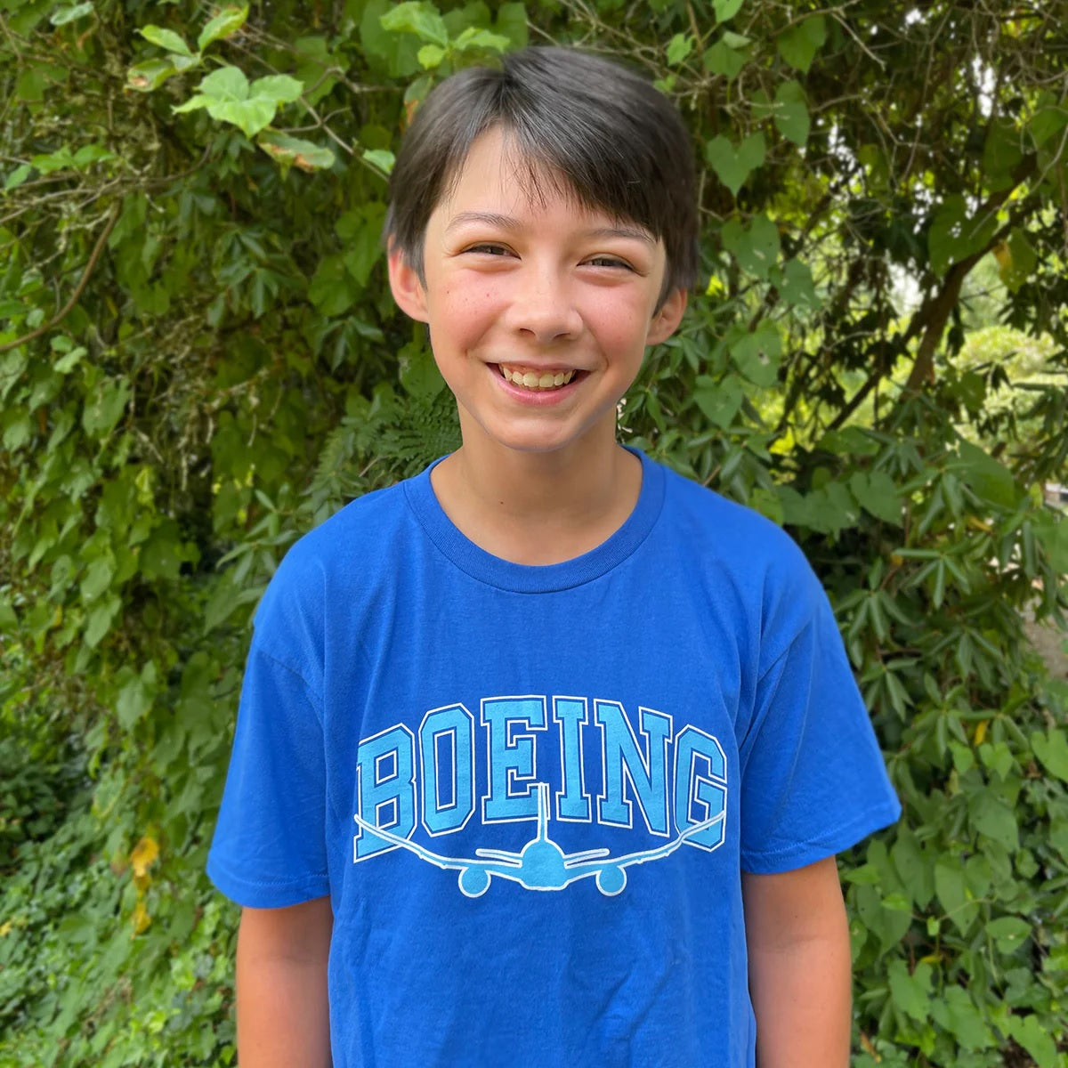 Child wearing Boeing Youth Varsity Graphic Tee in royal blue outdoors