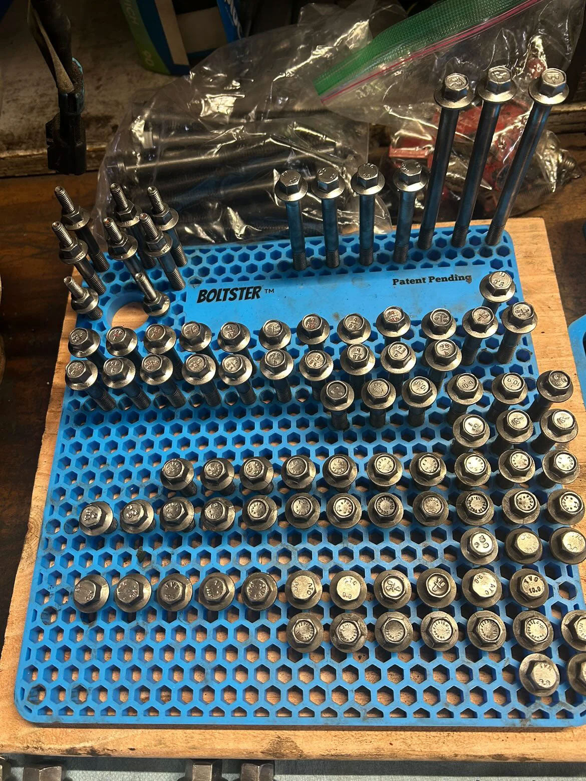 Blue Boltster Original Organizer fully loaded with bolts, showcasing its high-capacity hex pattern grid on a workbench.