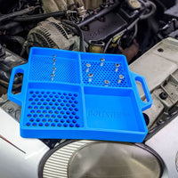 Boltster™ Flexible Organizing Tray in blue with bolts, placed on a vehicle engine during automotive maintenance
