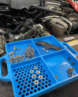 Boltster™ Flexible Organizing Tray filled with fasteners and parts, positioned on a vehicle during engine bay maintenance