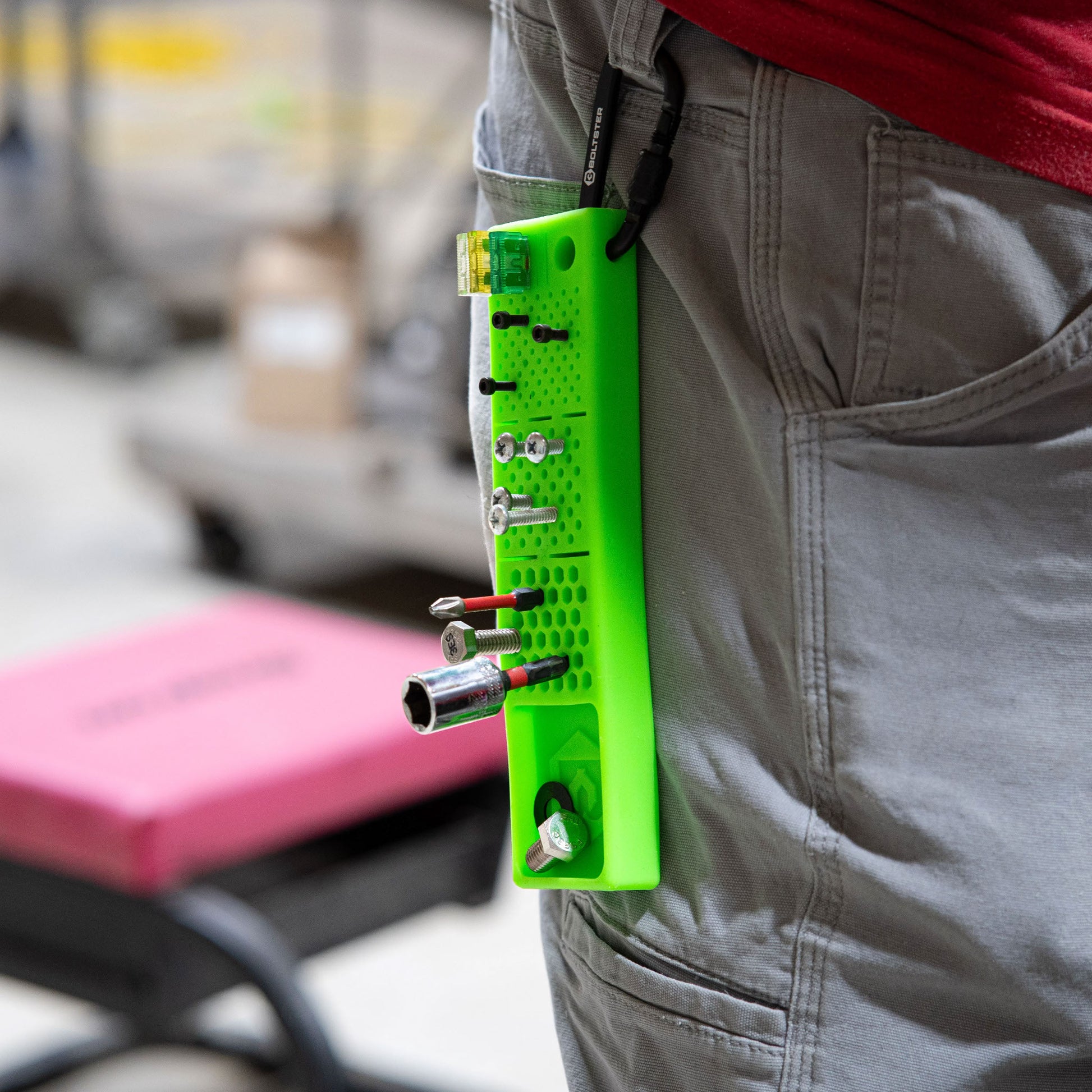 Green Bitster 2.0 fastener organizer clipped to technician’s pocket with bits and fuses