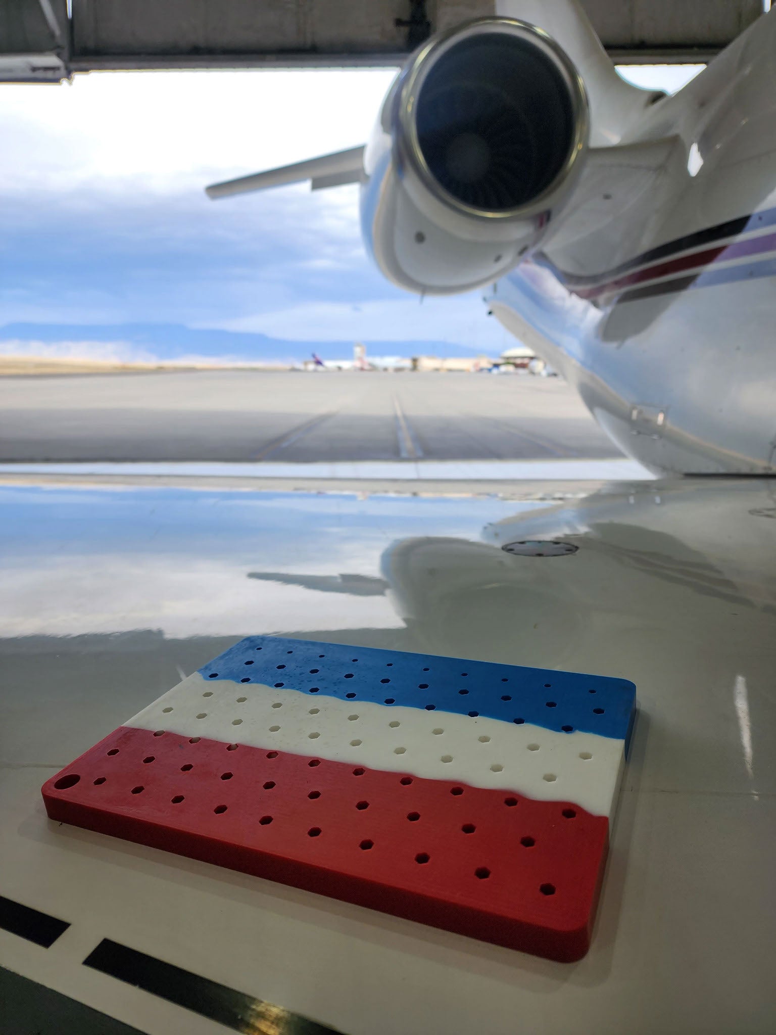 Boltster™ Air Force Organizer in red, white, and blue resting on aircraft surface with runway and jet engine in the background