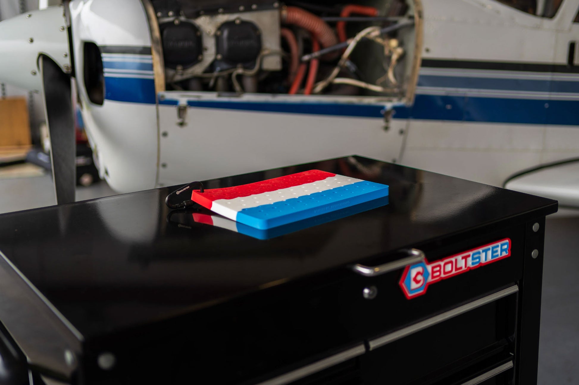 Boltster™ Air Force Organizer in red, white, and blue resting on a tool chest in front of an aircraft under maintenance