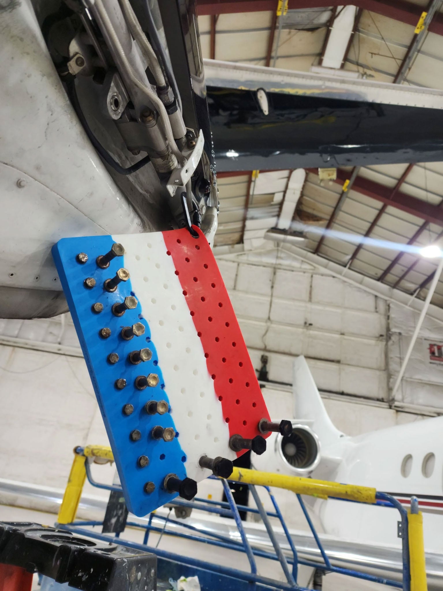 Boltster™ Air Force Organizer in use during aircraft maintenance, holding small fasteners and clipped to fuselage inside a hangar