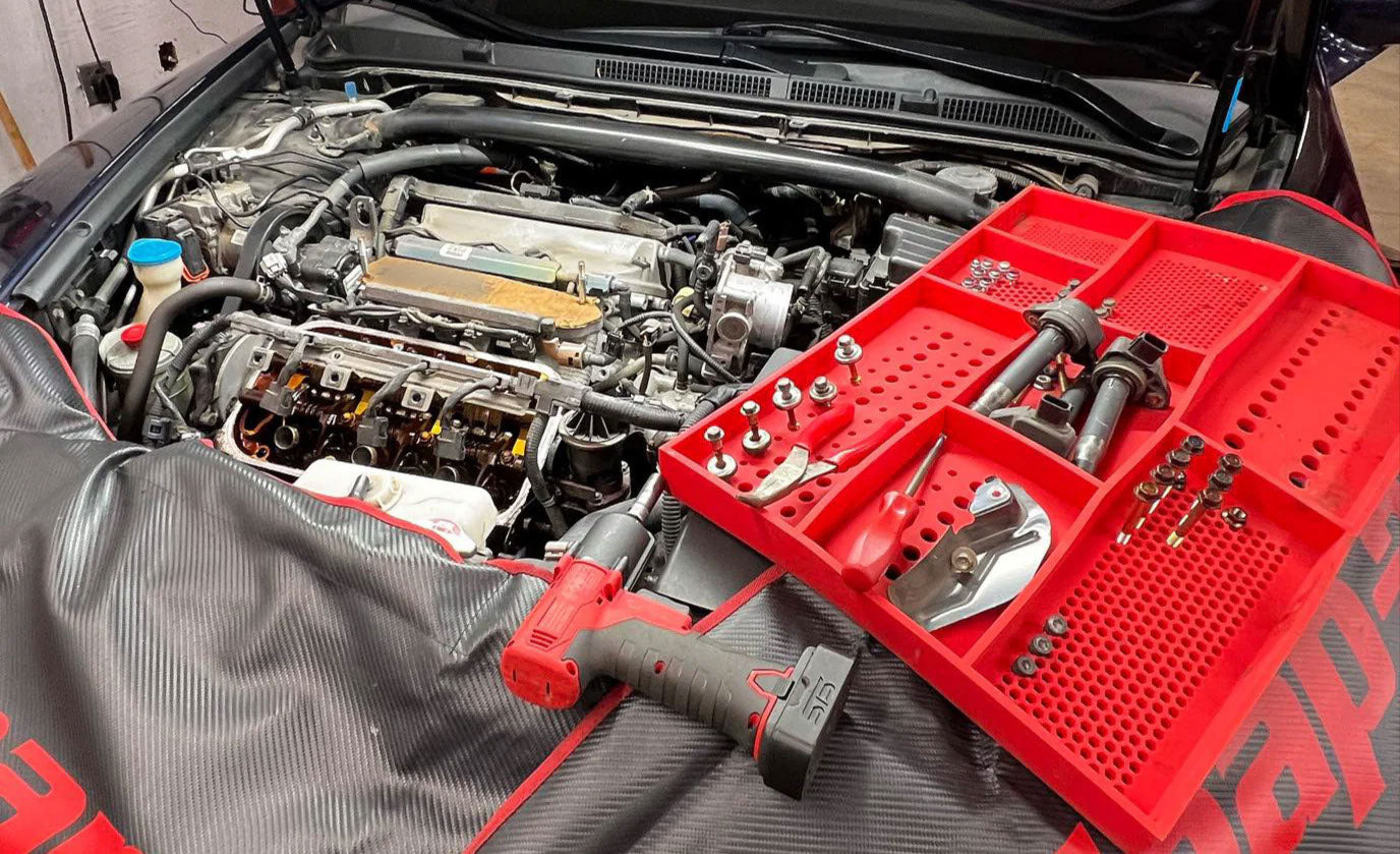 Boltster™ Top Box Tool Tray in red used during automotive engine work, holding tools, bolts, and parts in organized compartments
