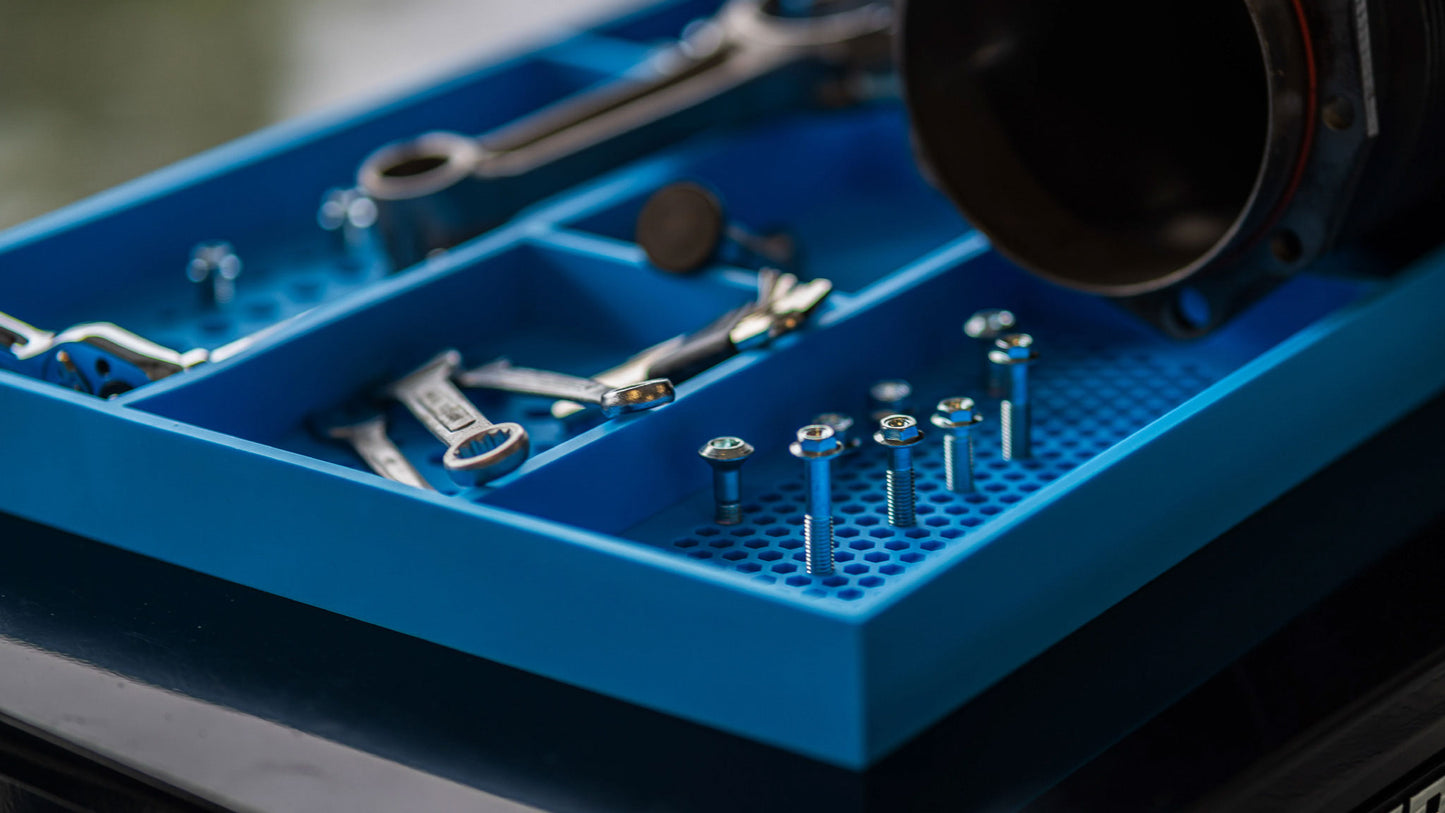 Close-up of Boltster™ Top Box Tool Tray in blue holding wrenches, screws, and fasteners during a mechanical project