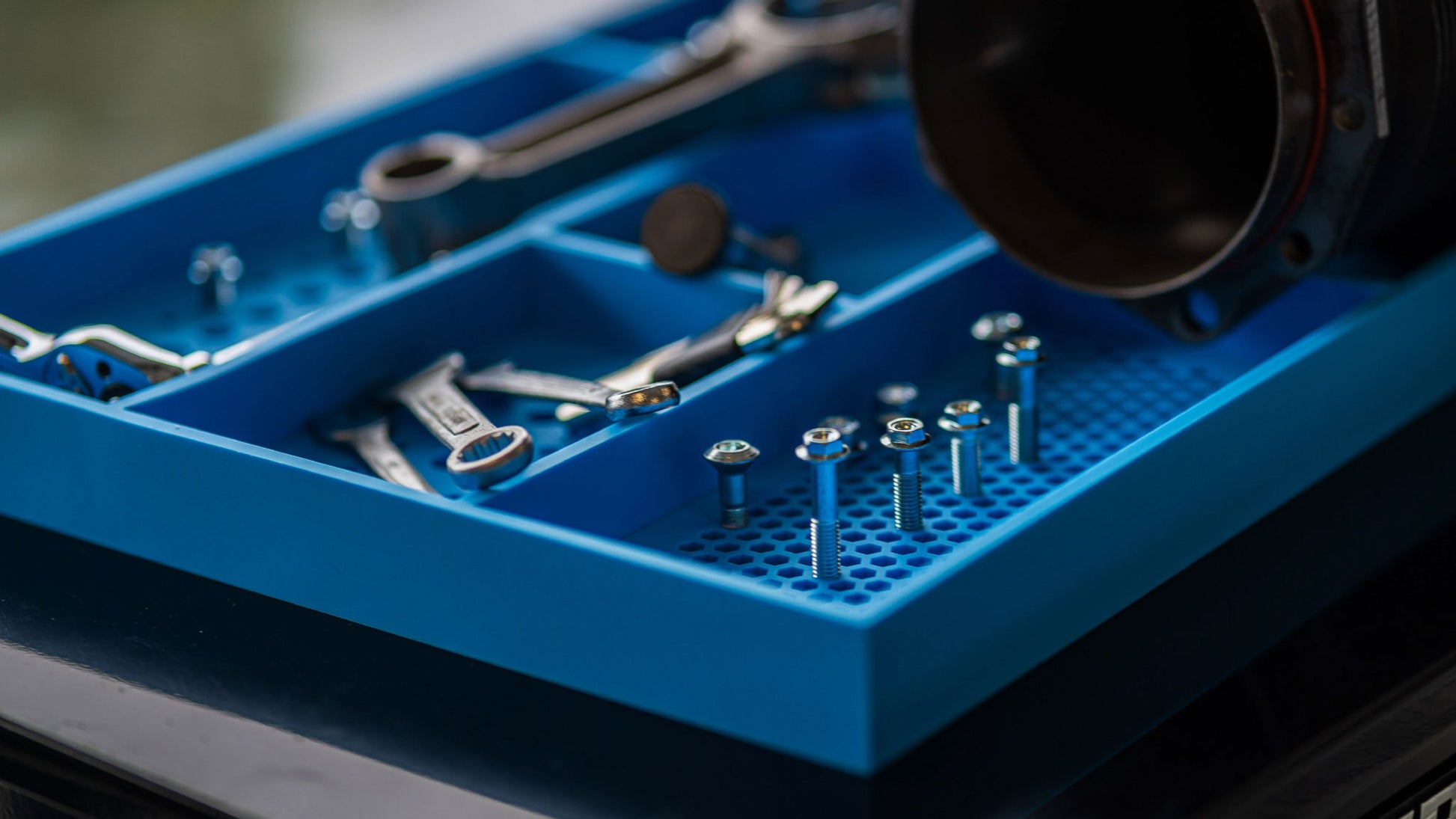 Close-up of Boltster™ Top Box Tool Tray in blue holding wrenches, screws, and fasteners during a mechanical project