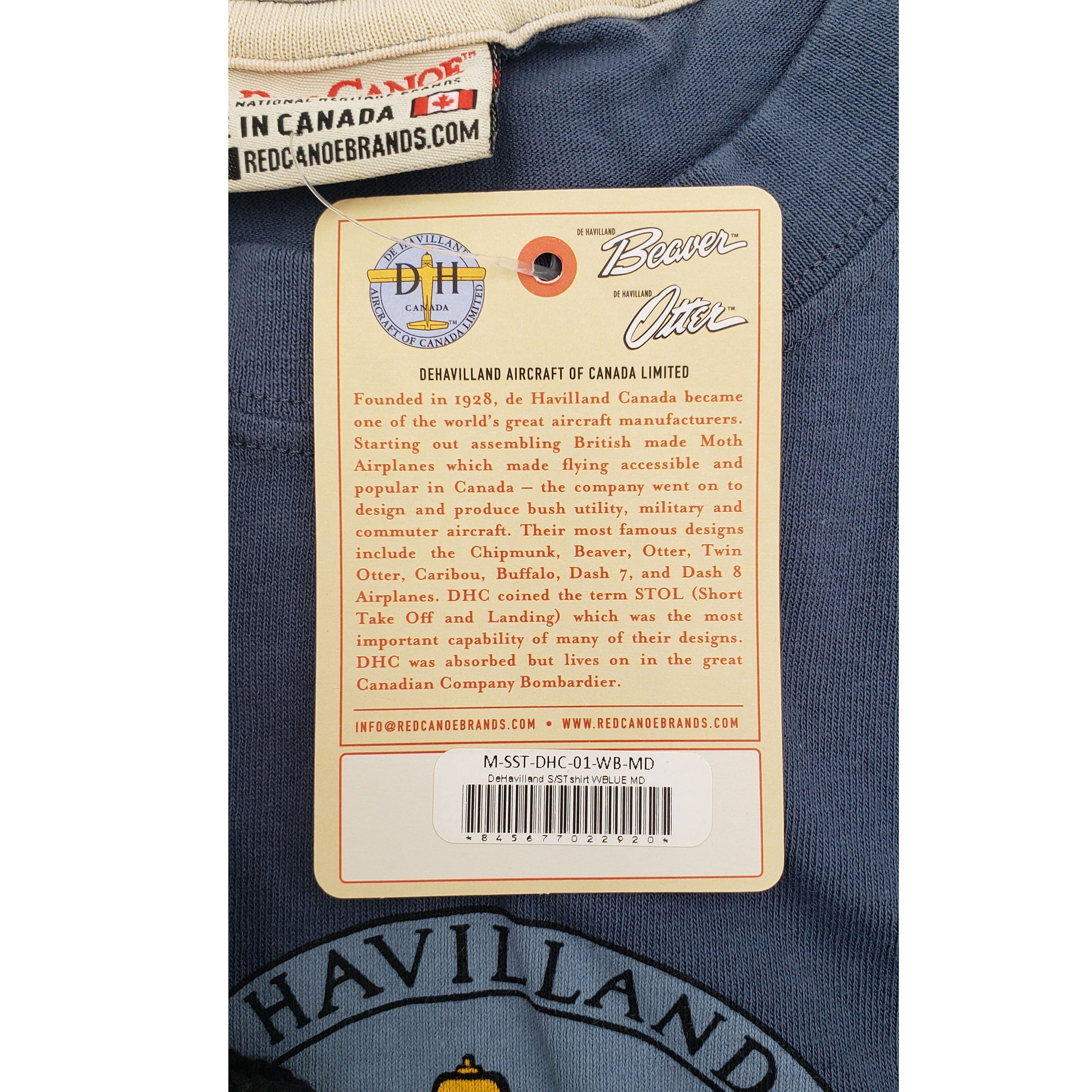 Interior label of Red Canoe De Havilland t-shirt showing brand tag, 100% cotton material, Made in Canada details