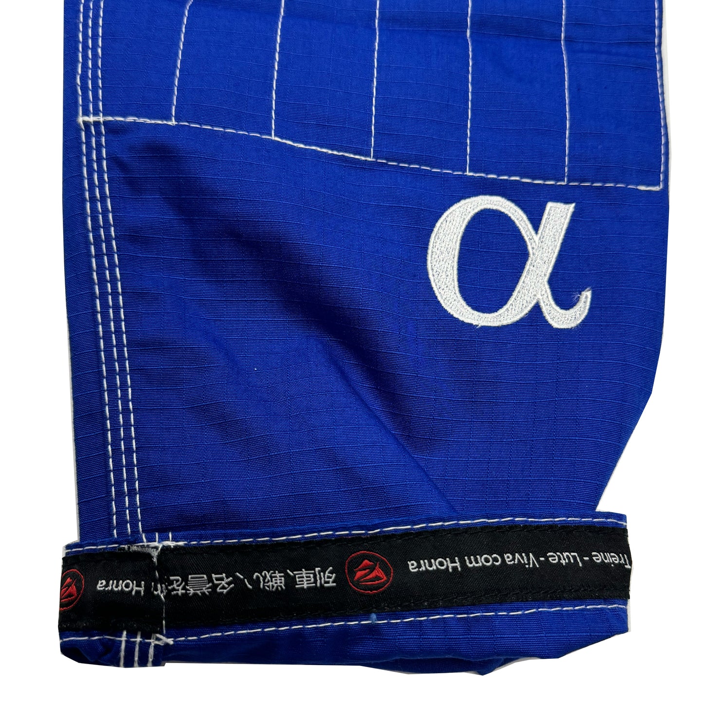 Zed Honra Women’s Alpha Gi – Close-Up of Blue BJJ Pants Cuff with Reinforced Stitching and ‘Train. Fight. Live with Honor’ Tagline in English, Japanese, and Portuguese