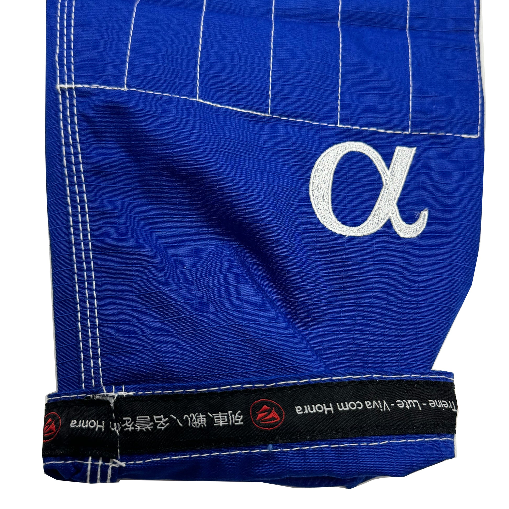 Zed Honra Women’s Alpha Gi – Close-Up of Blue BJJ Pants Cuff with Reinforced Stitching and ‘Train. Fight. Live with Honor’ Tagline in English, Japanese, and Portuguese