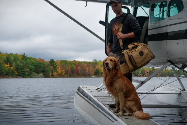 A man standing in front of an aircraft while wearing the Flight Outfitters Retro Logo Long Sleeve T-Shirt, reflecting its aviation-inspired style.