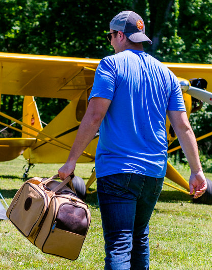 A man walking while holding the back of the Flight Outfitters Bush Pilot Duffel Bag, emphasizing its portability.