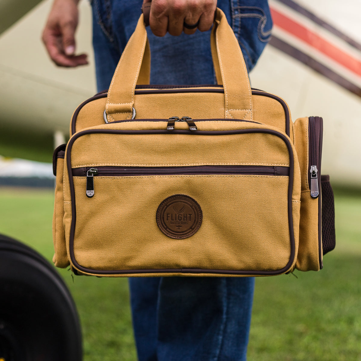 Detailed view of the man carrying the Flight Outfitters Bush Pilot Flight Bag, showing its leather handle and sturdy build.