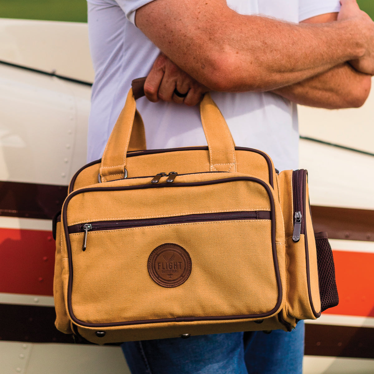 A man holding the Flight Outfitters Bush Pilot Flight Bag, emphasizing its portability and rugged style.