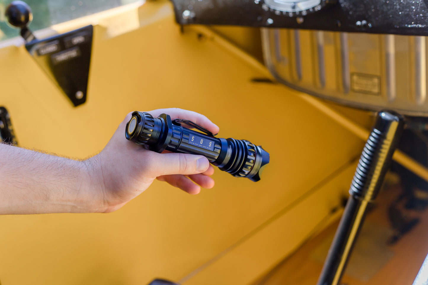 A man holding the Flight Outfitters Bush Pilot Flashlight, demonstrating its portable and rugged design.