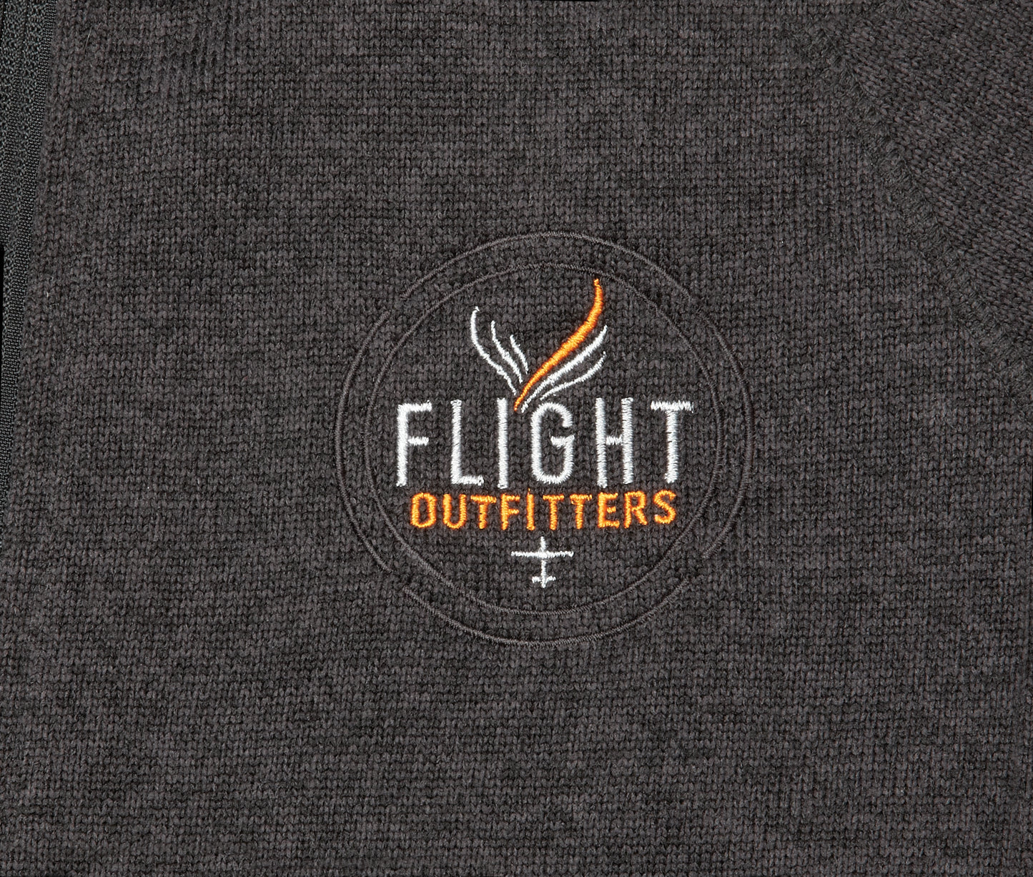 Close-up view of the Flight Outfitters logo on the Women's Fairbanks Fleece in Heather Obsidian, emphasizing branding details.