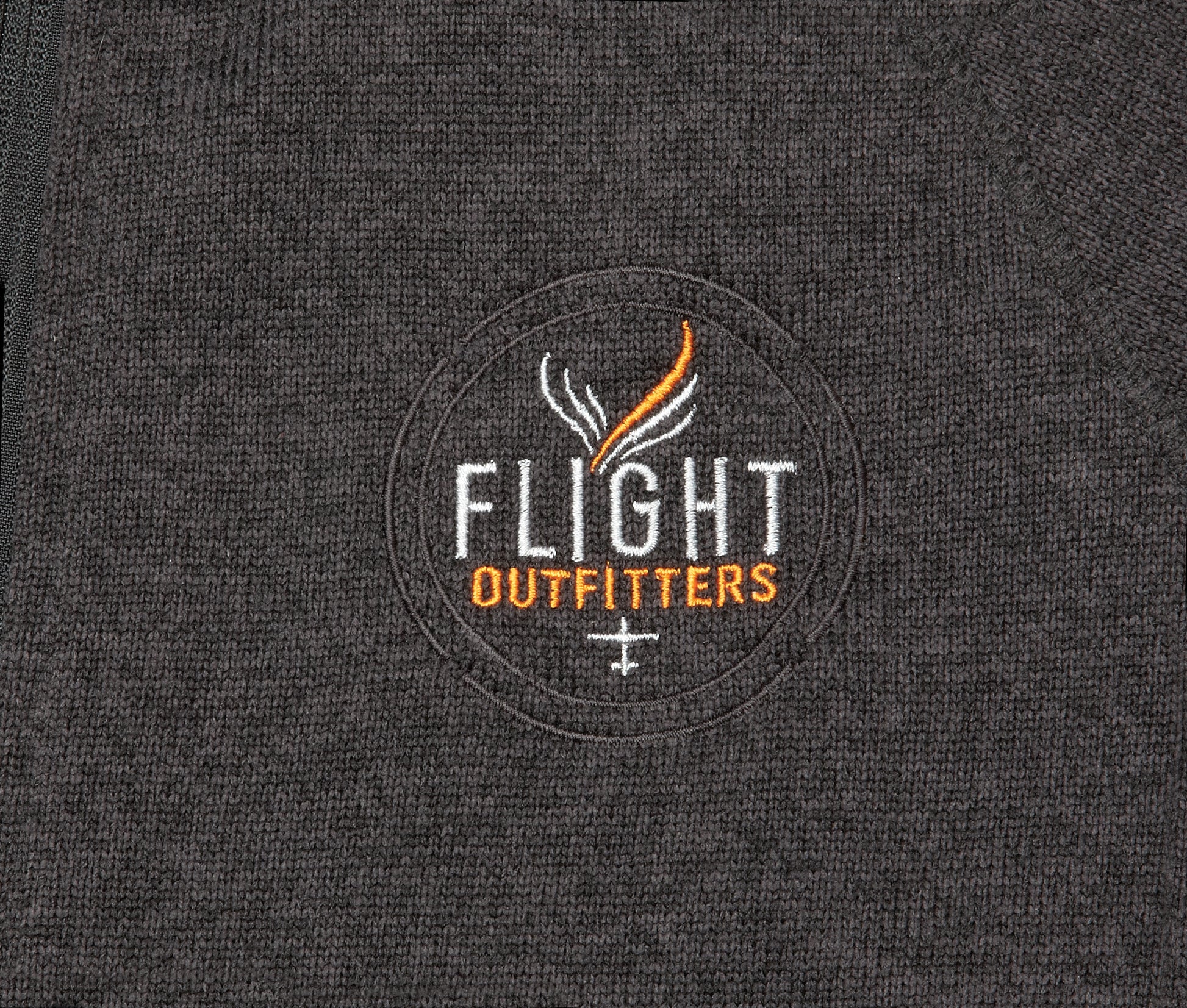 Close-up view of the Flight Outfitters logo on the Women's Fairbanks Fleece in Heather Obsidian, emphasizing branding details.