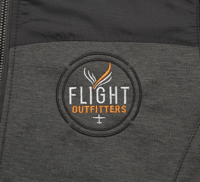 Close-up embroidered Flight Outfitters logo on Men's Kodiak Jacket – circular patch with white and orange text on dark gray fabric
