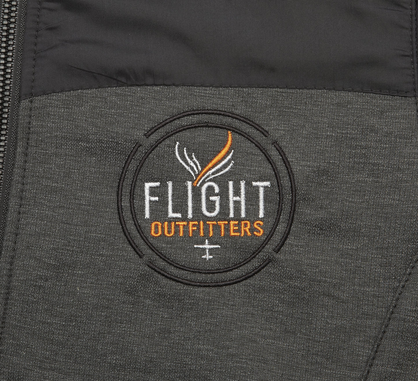 Close-up embroidered Flight Outfitters logo on Women's Kodiak Jacket – circular patch with white and orange text on gray fabric