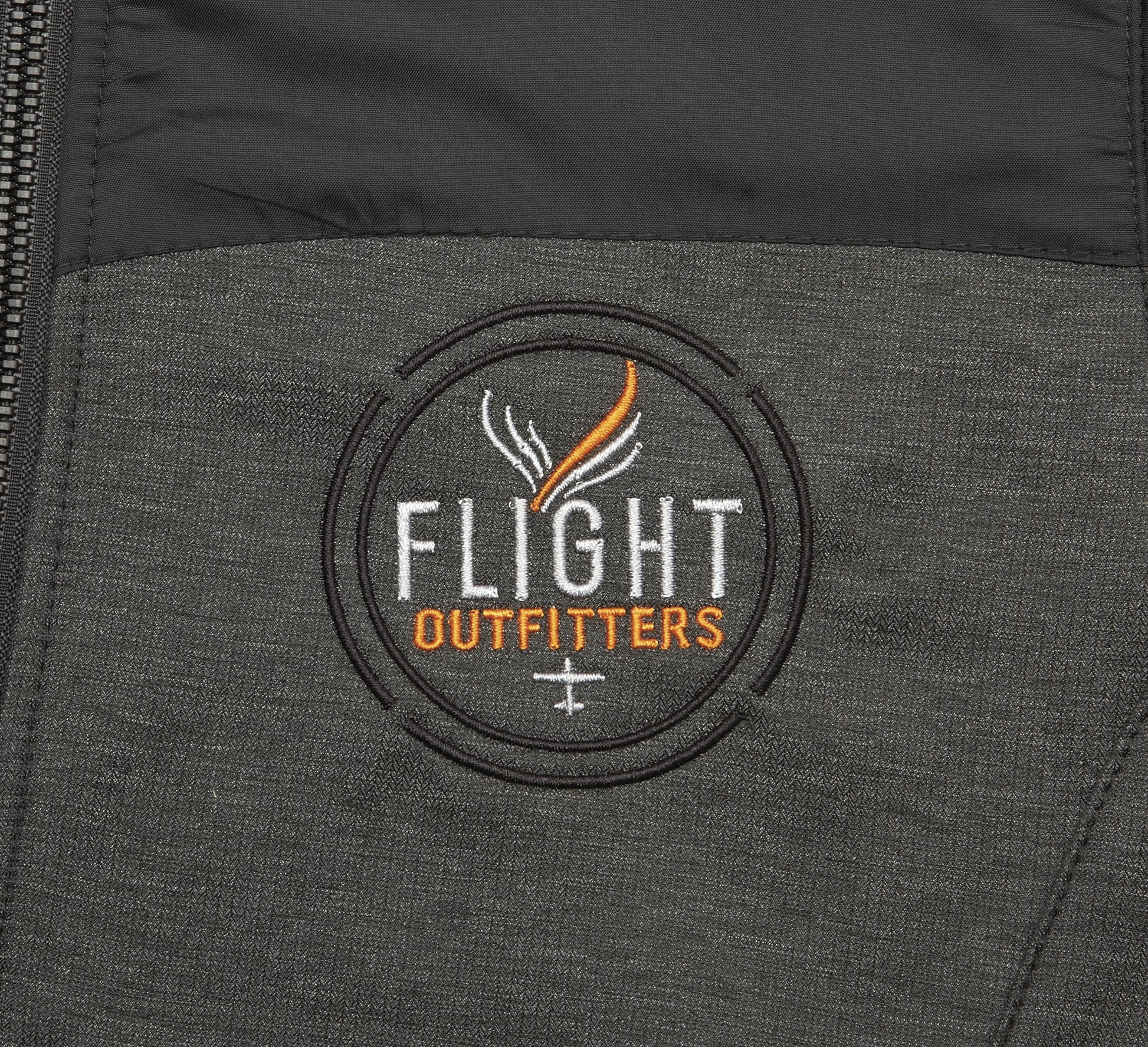 Close-up embroidered Flight Outfitters logo on Women's Kodiak Jacket – circular patch with white and orange text on gray fabric