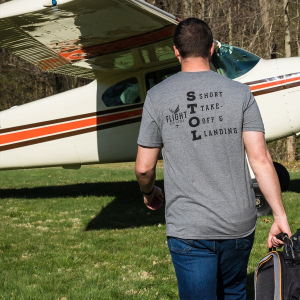 Man wearing Flight Outfitters 'Fly It Like You STOL It' T-Shirt walking towards aircraft