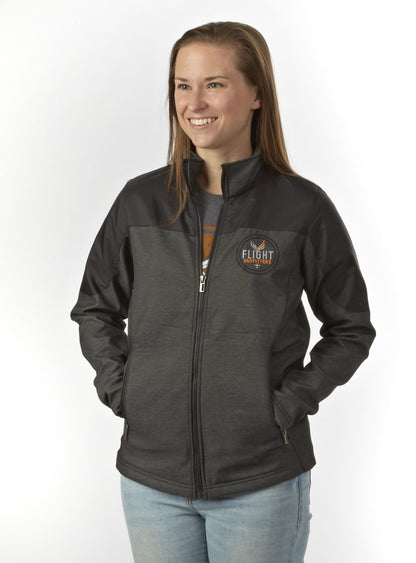 Studio portrait variation – woman smiling in Flight Outfitters Women's Kodiak Jacket, dark gray with black accents, logo on chest