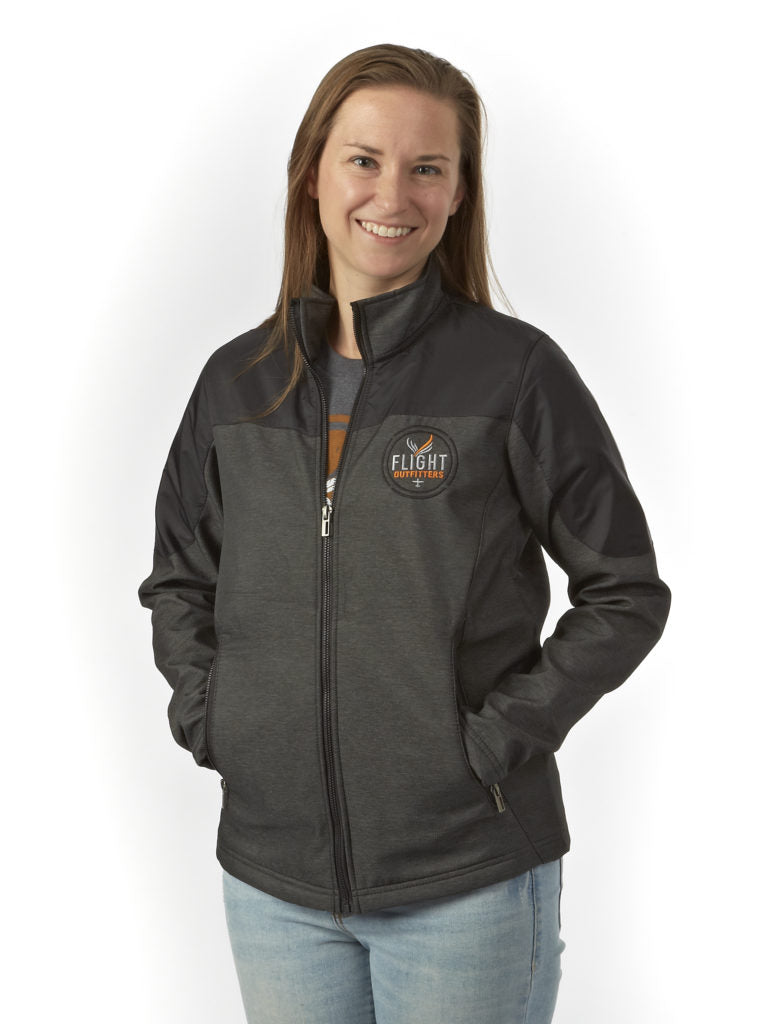 Studio portrait – woman wearing Flight Outfitters Women's Kodiak Jacket, dark gray with black shoulders, hands in pockets, white background