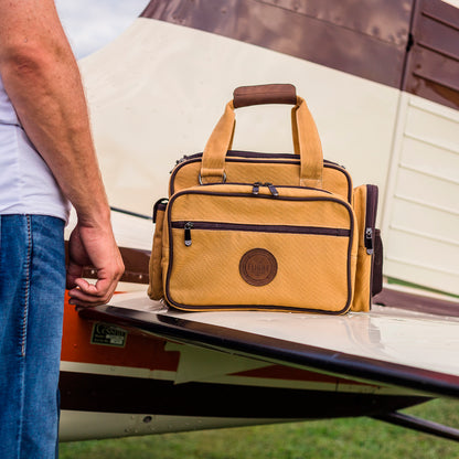 Flight Outfitters Bush Pilot Flight Bag resting on the wing of an aircraft, demonstrating its aviation-centric design.
